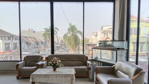 A spacious room with a large window offering a view of the cityscape, a sofa set, a small table with a vase, and a fish tank. - The Vinci Hotel powered by Cocotel (Jakarta)