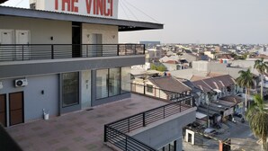 A building with a sign reading "THE VINCI" and a view of a residential area with houses and palm trees. - The Vinci Hotel powered by Cocotel (Jakarta)