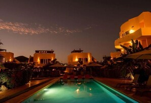 Relax by the pool surrounded by lush greenery and comfortable lounge chairs.