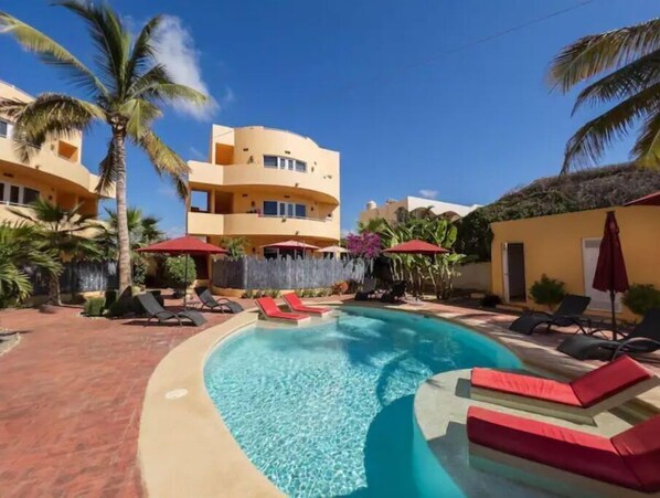 Relax by the resort's pool surrounded by palm trees and lounge chairs.