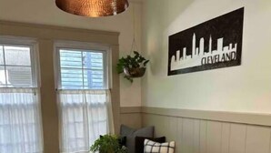 A dining area with a round table, black chairs, a hanging light fixture, a bench with cushions, and a city skyline painting on the wall. - Cleveland Hideaway on Clifton (Cleveland)