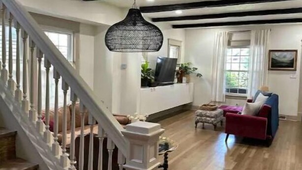 A spacious living area with a staircase, wooden flooring, and a modern pendant light. - Cleveland Hideaway on Clifton (Cleveland)