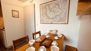 Ett matbord dukat för fyra personer med vita tallrikar och bestick, en karta på väggen och en liten inramad tavla på väggen.