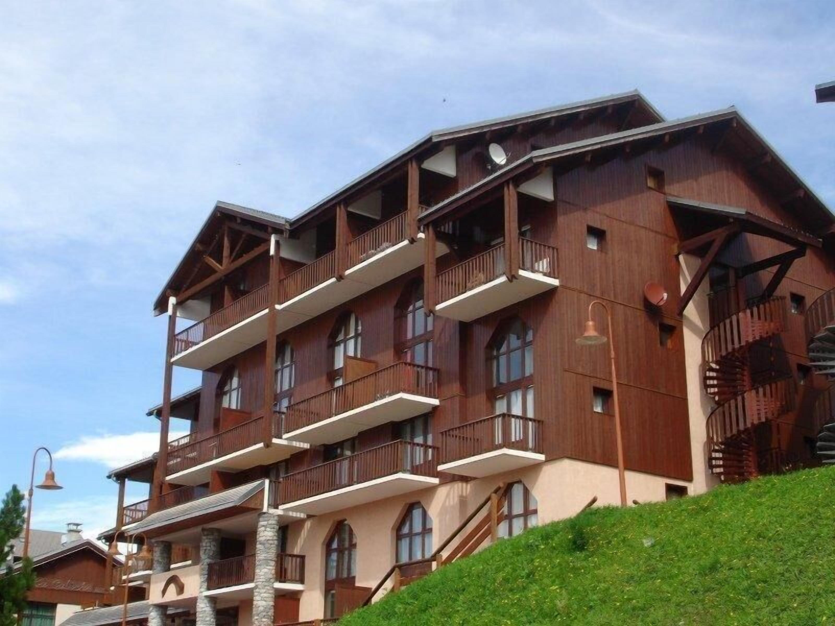 A multi-story wooden building with balconies, a stone base, and a staircase leading to the upper floors.