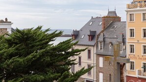 A coastal building with a stone facade, multiple windows, and a balcony. - Starfish - Charmant appt à 3min à pied de la plage (Saint-Malo)