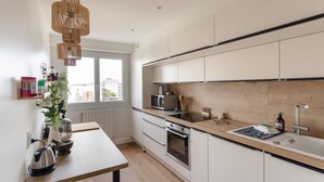 A modern kitchen with a wooden countertop, stainless steel appliances, and a large window providing natural light. - Starfish - Charmant appt à 3min à pied de la plage (Saint-Malo)