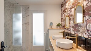 A modern bathroom with a glass shower enclosure, two sinks, and a decorative mirror. - Starfish - Charmant appt à 3min à pied de la plage (Saint-Malo)