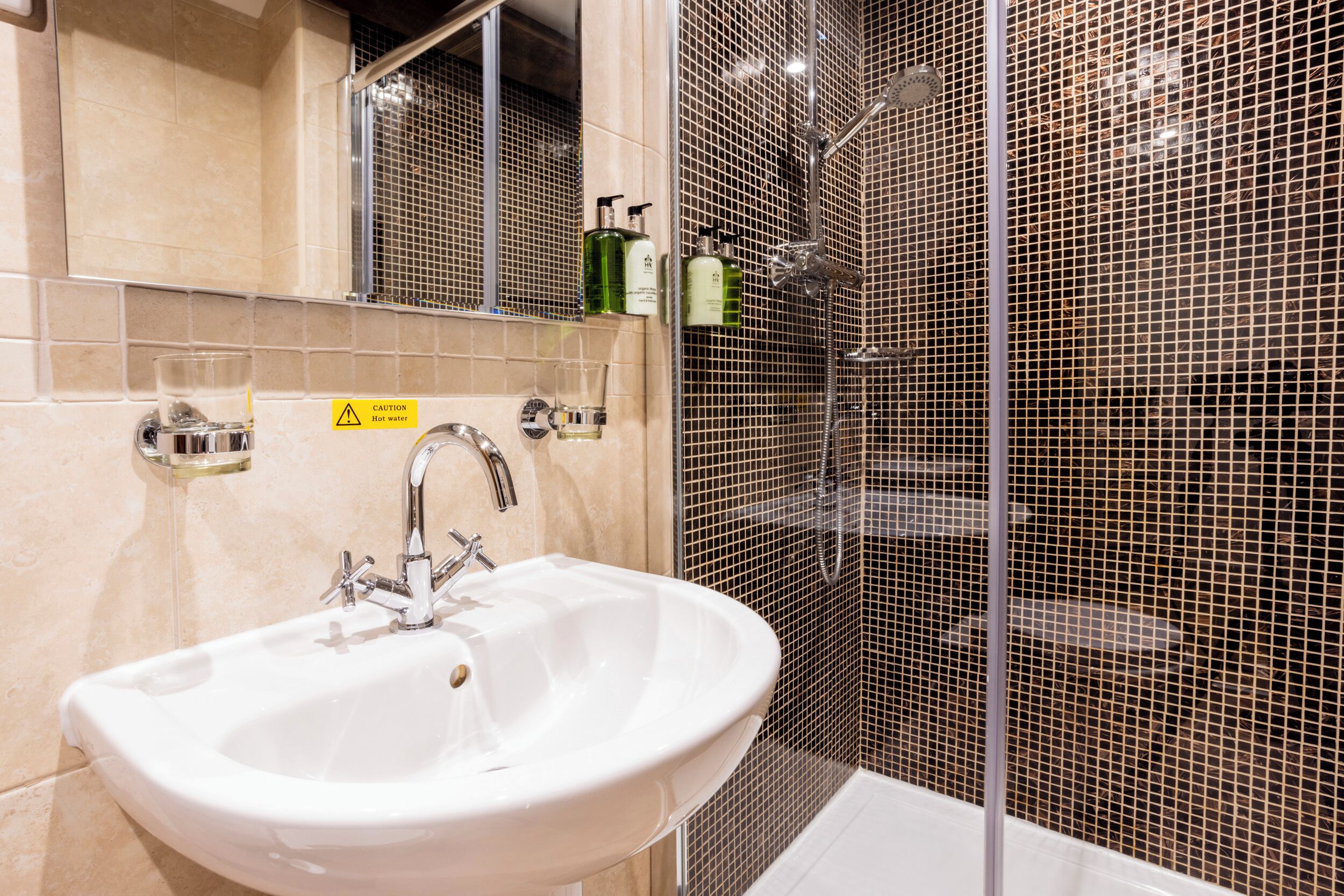A bathroom with a white sink, mirror, and tiled walls.