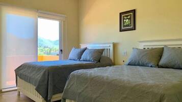 A bedroom with two beds, a window, and a framed picture on the wall.