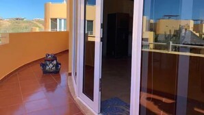 A balcony with a tiled floor, a small table with a chair, and a glass door leading to an interior space. - 3B Cerritos Beach Condo, Lrg Pool, Baja Sur (El Pescadero)