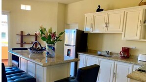 A kitchen with a central island, white cabinets, a refrigerator, a coffee maker, and a vase with flowers. - 3B Cerritos Beach Condo, Lrg Pool, Baja Sur (El Pescadero)