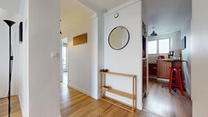 Una cocina moderna con suelo de madera, un espejo redondo y un taburete rojo.