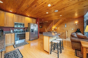 A kitchen with wooden cabinets, a microwave, a refrigerator, and a stove.