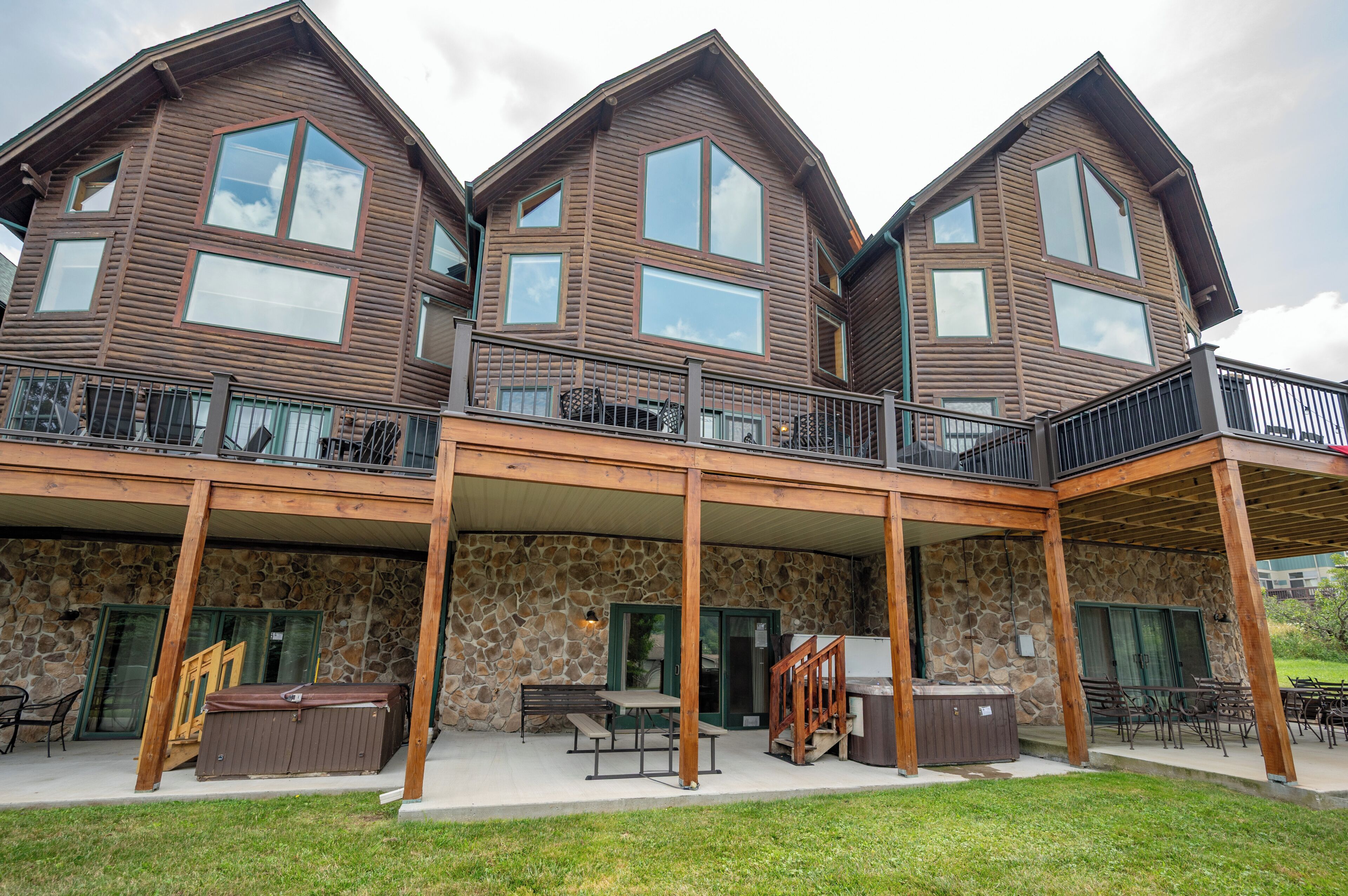 A multi-story building with a stone facade, wooden balconies, and outdoor seating areas.