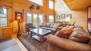 Ein Blockhaus-Interieur mit einer Sofagarnitur, einem Couchtisch und einer Lampe.