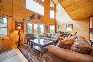 A log cabin interior with a sofa set, a coffee table, and a lamp.
