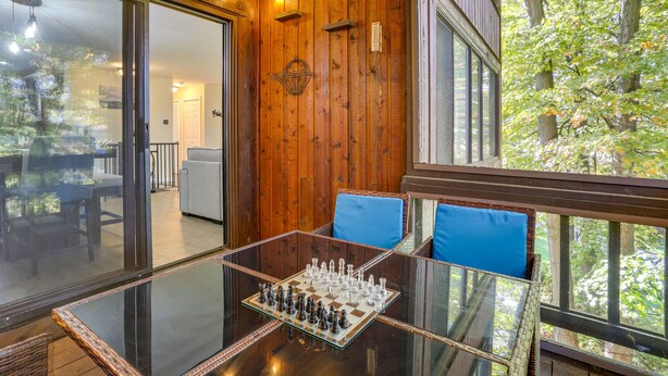 Un tavolo con piano in vetro, una scacchiera, pareti in legno e cuscini blu.