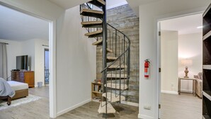 Un interno moderno con una scala a chiocciola, pavimento in legno, una libreria e un letto.