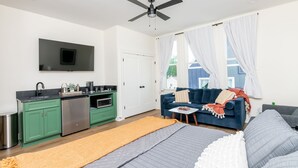Ein modernes Apartment mit Küchenzeile, einem Wohnbereich mit Sofa und Couchtisch sowie einem Bett mit großem Fenster.
