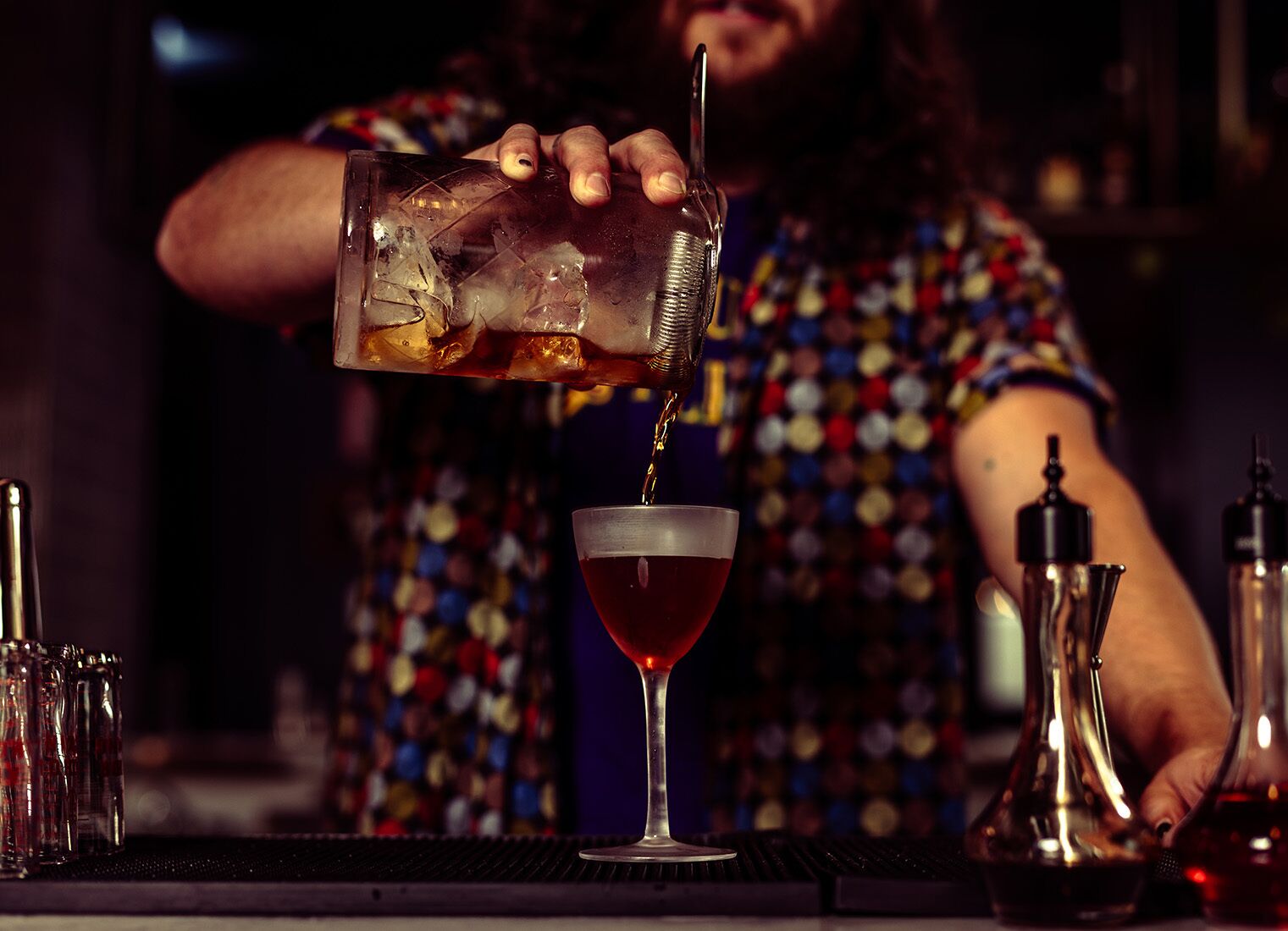 Un bartender sirve una bebida en una copa de martini.
