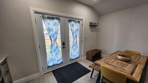 Un comedor con una mesa de madera y sillas amarillas, un banco de madera pequeño y una alfombra negra.