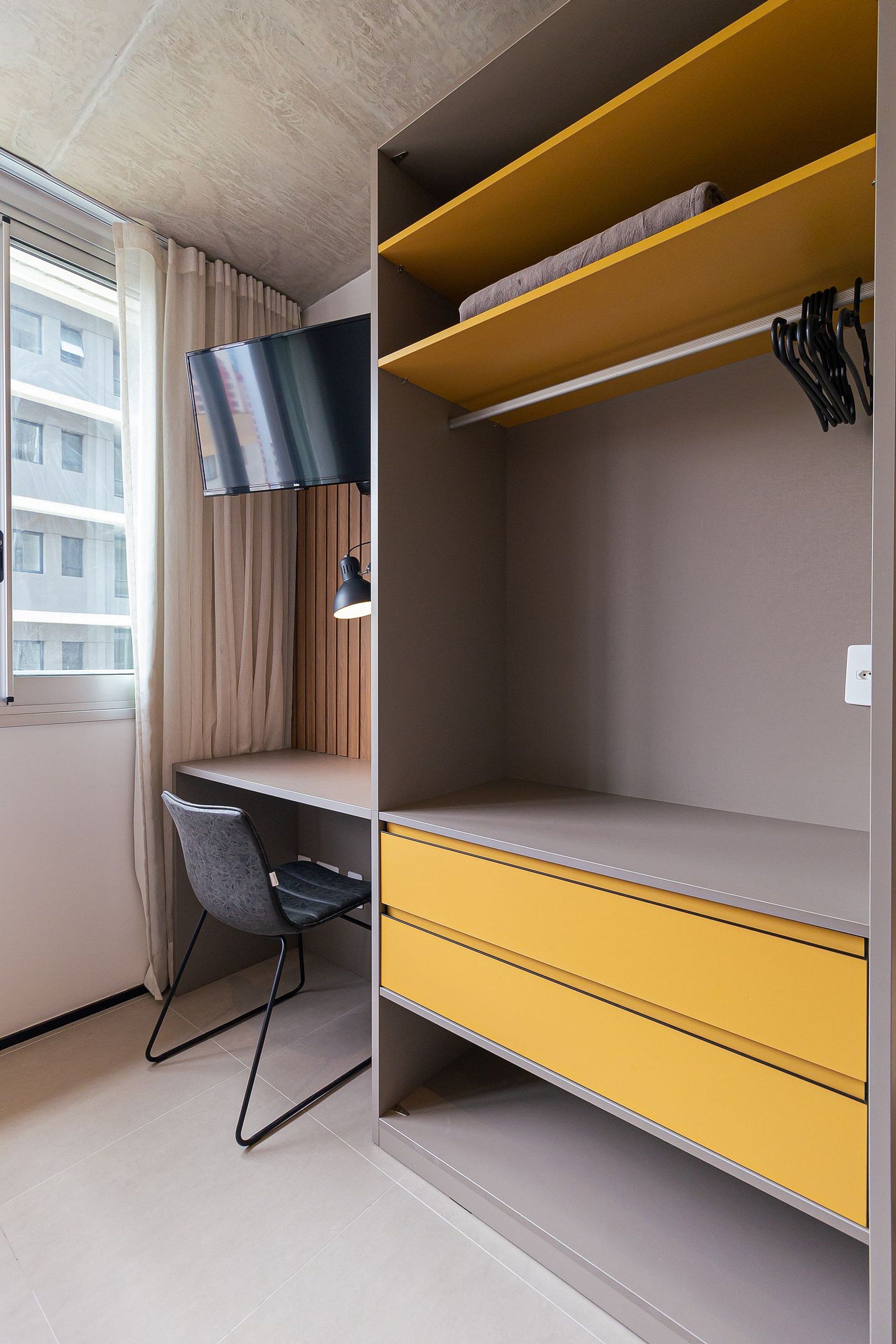 A compact room with a desk, chair, and built-in shelving.