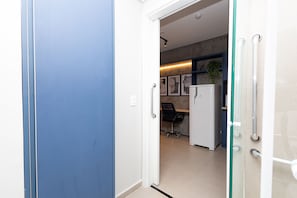 A modern kitchen with a refrigerator, a chair, and a plant.