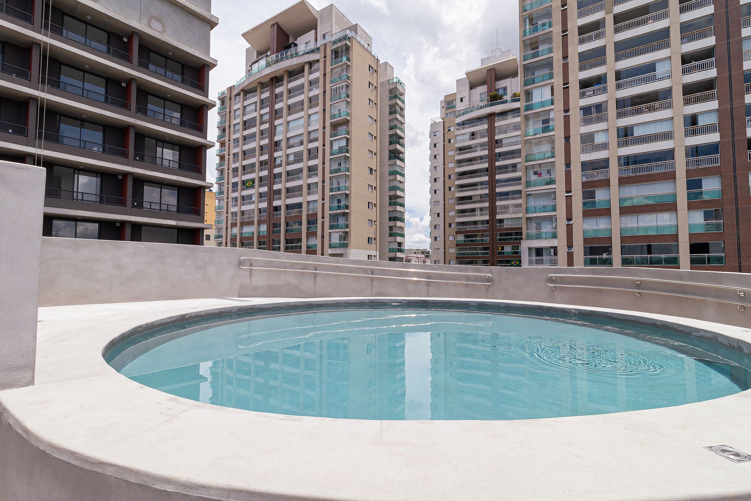 A rooftop swimming pool with a view of high-rise residential buildings.