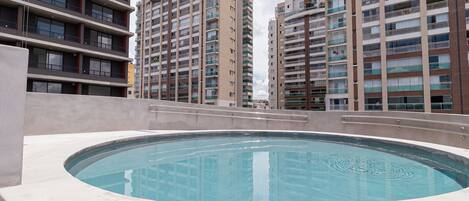 A rooftop swimming pool with a view of high-rise residential buildings.