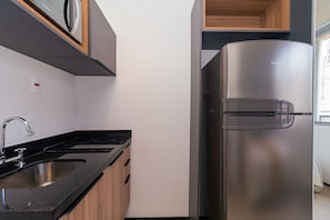 A modern kitchen with a stainless steel refrigerator, a double sink, and wooden cabinets. - Vossa Bossa Chez Frei (São Paulo)