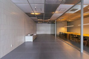 A modern interior with a long, narrow room featuring a sofa, a glass partition, and a long table with chairs.