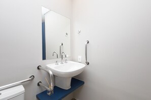 Un baño con lavamanos blanco, un espejo y encimera azul.