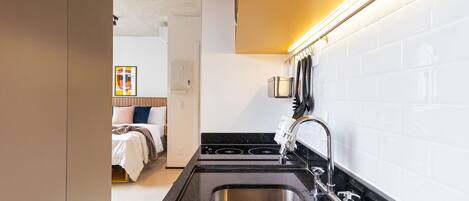 A compact kitchen with a stainless steel sink, a stove, and a modern faucet.