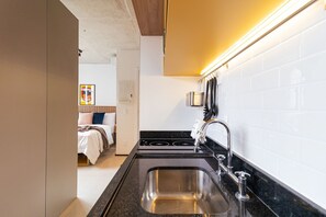 A compact kitchen with a stainless steel sink, a stove, and a modern faucet. - Vossa Bossa Chez Frei (São Paulo)