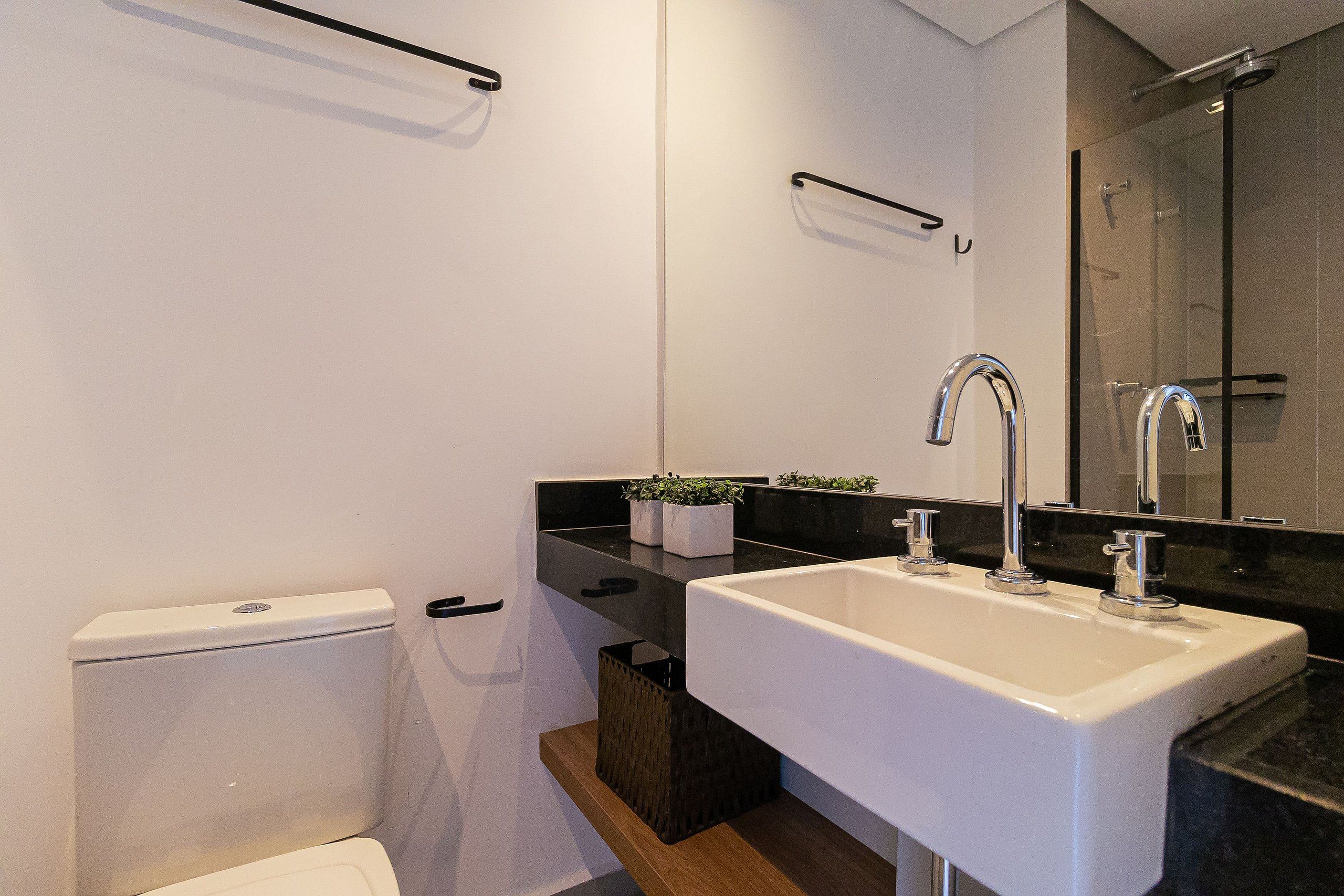 Un bagno moderno con lavandino bianco, piano di lavoro nero e box doccia in vetro.