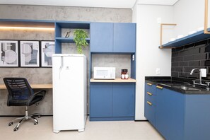 A modern kitchen with blue cabinets, a white refrigerator, a microwave, and a coffee maker. - Vossa Bossa Chez Frei (São Paulo)