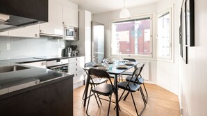 A modern kitchen with a dining area, large windows, and a view of the outside. - 2ndhomes Modern & Cozy 2BR Apt w Balcony (Helsinki)