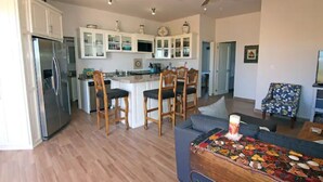 A modern kitchen with white cabinets, a refrigerator, and a dining area with wooden chairs.