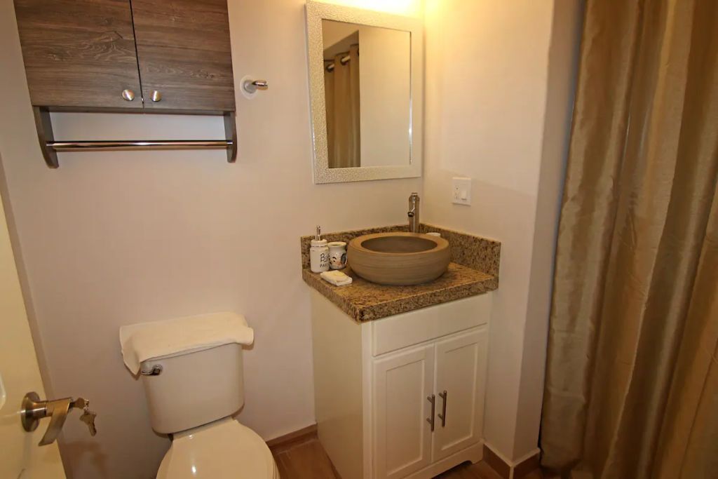 Ein Badezimmer mit Toilette, Waschbecken, Spiegel und Schrank.