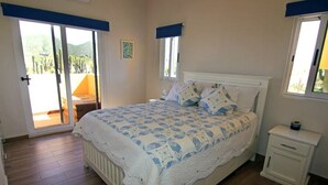 A bedroom with a bed, a nightstand, a window, and a door leading to a balcony.