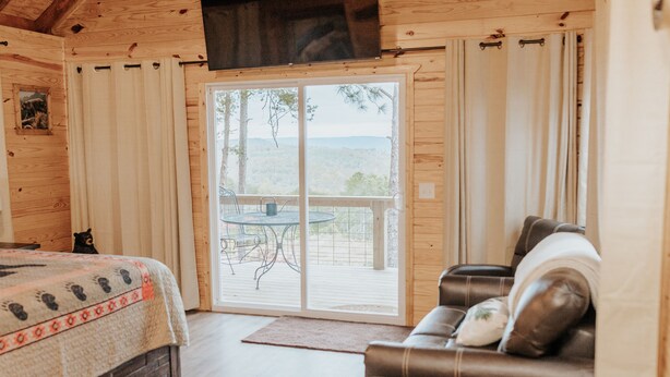 Una cabina con interni in legno, un letto con coperta fantasia, un divano in pelle e un patio con tavolo e sedie.
