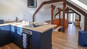 Eine moderne Küche mit einer zentralen Kochinsel, einem eingebauten Backofen und einer großen schwarzen Dunstabzugshaube.