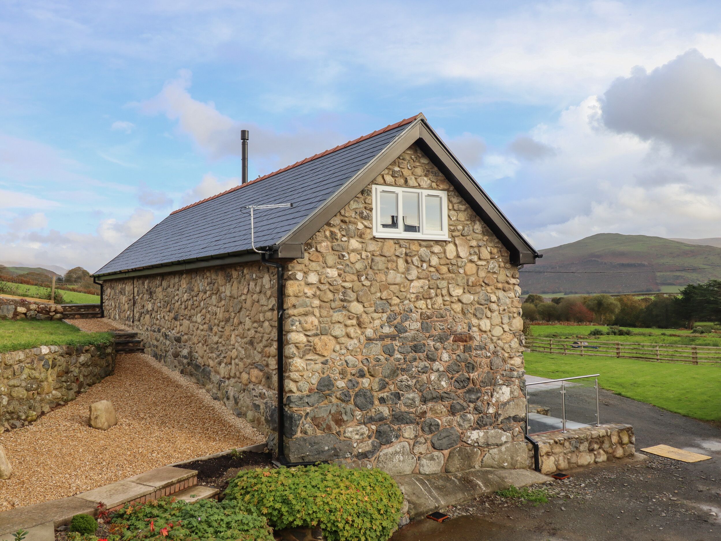 A stone cottage with a sloped roof, a small window, and a chimney.