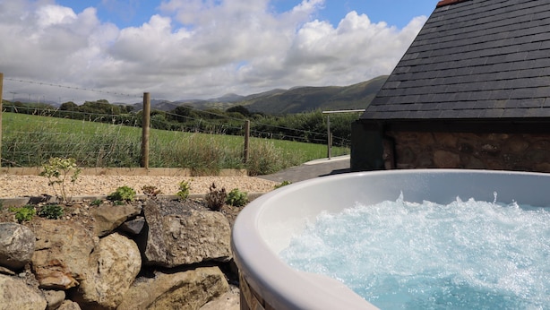 Ein Whirlpool mit Steinwand und Blick auf Weinberg und Berge.