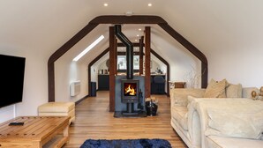 Ein gemütliches Loftsessel-Wohnzimmer mit Kamin, Holzmöbeln und Fernseher.