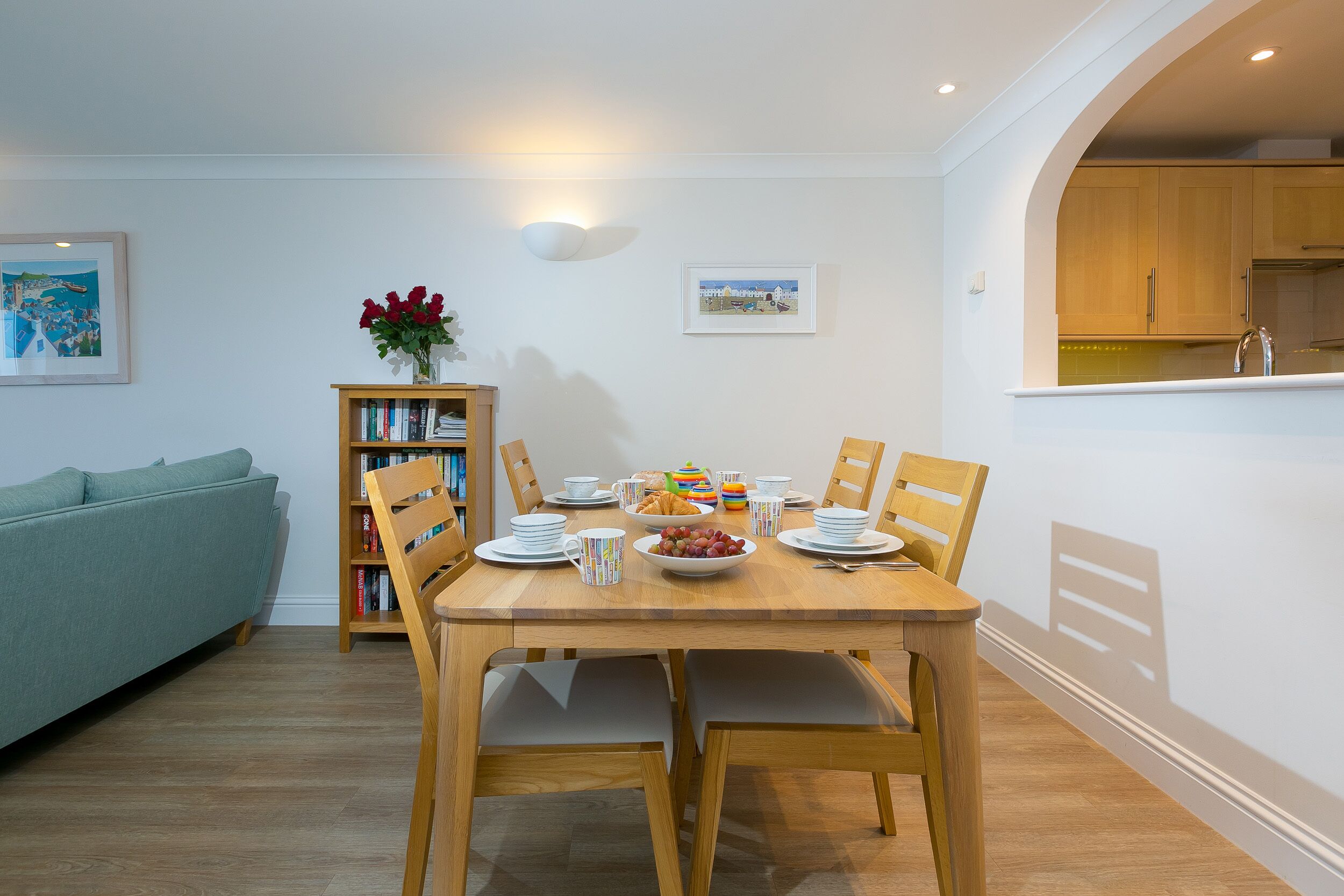 A dining area with a wooden table, chairs, and a bookshelf.
