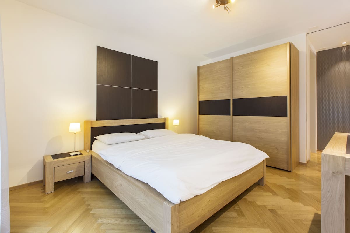 Une chambre Ă coucher moderne avec un lit en bois, des tables de chevet et une armoire.