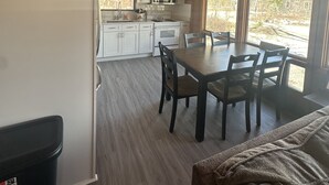 A modern kitchen with white cabinets, a microwave, and a dining area with a table and chairs.