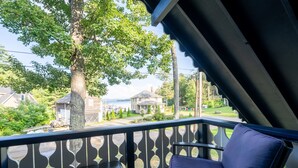 A balcony with a view of a residential area, including houses and a body of water.