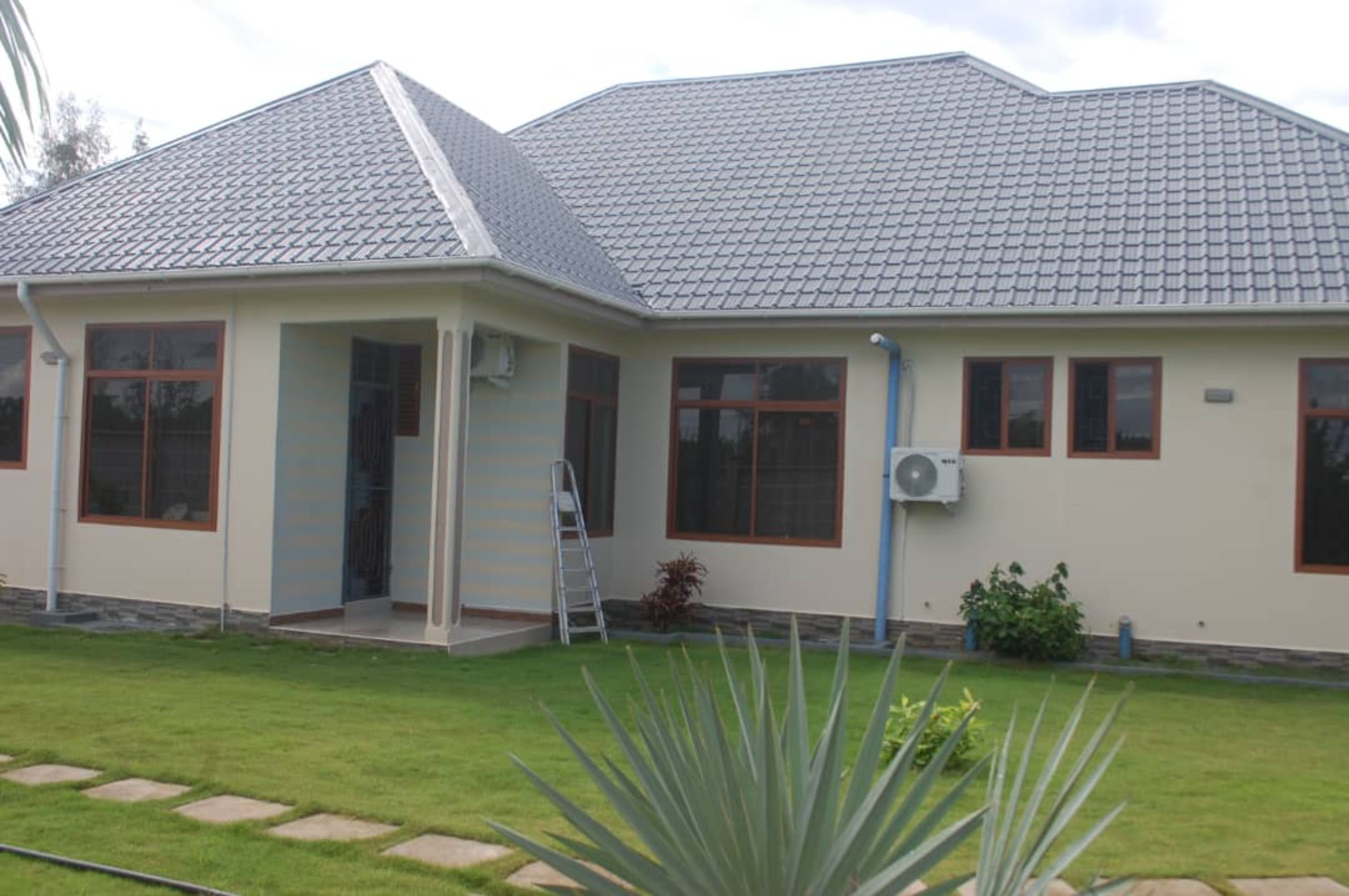 Een modern huis met een grijze betegelde kap, grote ramen en een verzorgd gazon.
